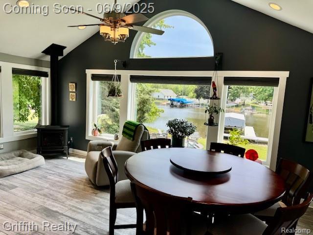 1158 Camelot Dr, Pinckney, MI 48169 - dining area with a wood stove, a ceiling fan, plenty of natural light, wood finished floors, and high vaulted ceiling