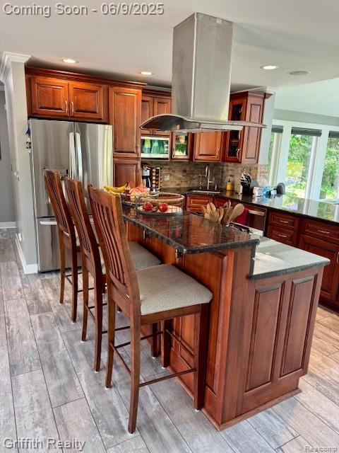 1158 Camelot Dr, Pinckney, MI 48169 - kitchen featuring appliances with stainless steel finishes, island range hood, a sink, a kitchen island, and tasteful backsplash