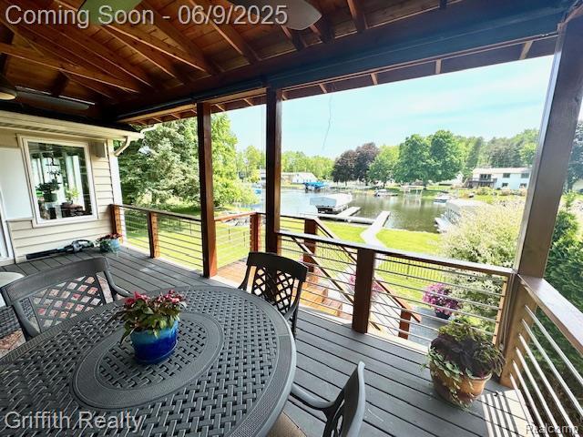 1158 Camelot Dr, Pinckney, MI 48169 - deck featuring a water view, outdoor dining space, and view of scattered trees
