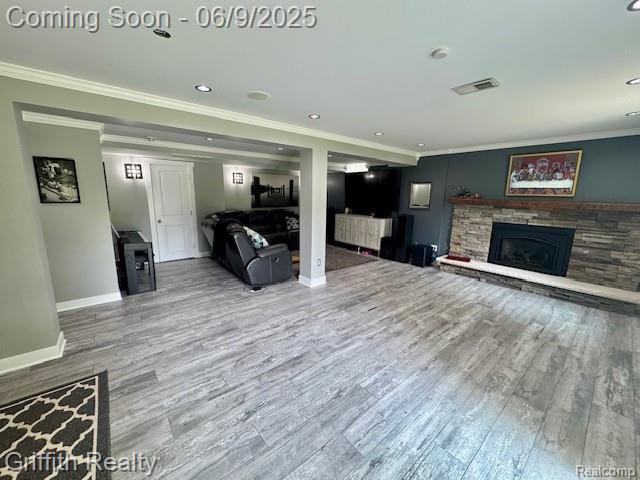 1158 Camelot Dr, Pinckney, MI 48169 - living room with a stone fireplace, ornamental molding, baseboards, wood finished floors, and recessed lighting