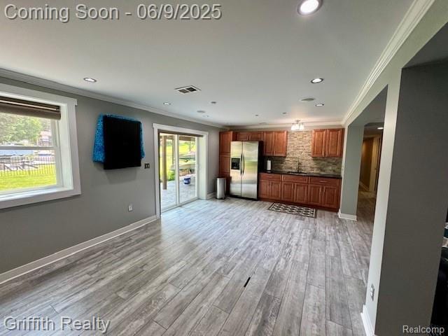 1158 Camelot Dr, Pinckney, MI 48169 - unfurnished living room with plenty of natural light, a sink, light wood-style floors, recessed lighting, and crown molding