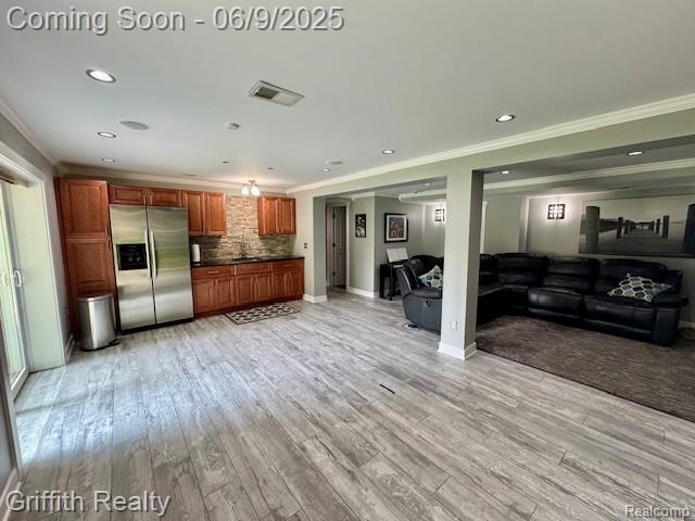 1158 Camelot Dr, Pinckney, MI 48169 - kitchen featuring stainless steel fridge with ice dispenser, ornamental molding, open floor plan, decorative backsplash, and light wood-type flooring