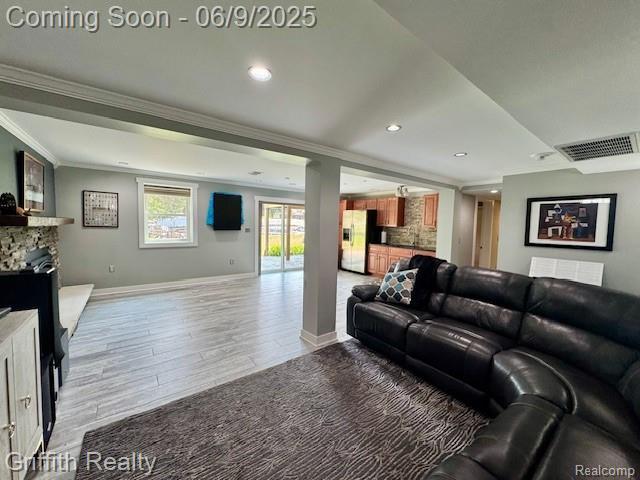 1158 Camelot Dr, Pinckney, MI 48169 - living room featuring ornamental molding, light wood-style flooring, baseboards, recessed lighting, and a stone fireplace