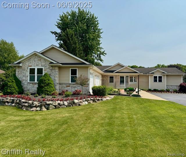 1158 Camelot Dr, Pinckney, MI 48169 - view of front of home with an attached garage, a front lawn, and stone siding