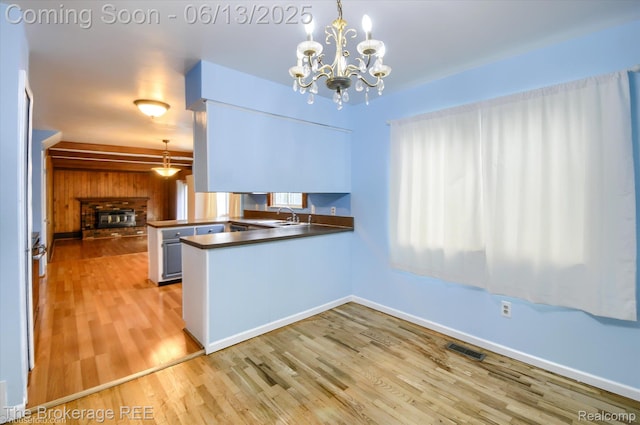 732 E Grand Blanc Rd, Grand Blanc, MI 48439 - kitchen with a sink, a peninsula, dark countertops, light wood-style floors, and a chandelier