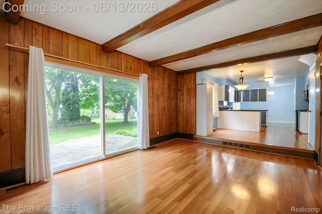 732 E Grand Blanc Rd, Grand Blanc, MI 48439 - unfurnished living room with light wood finished floors, beam ceiling, baseboards, and wooden walls