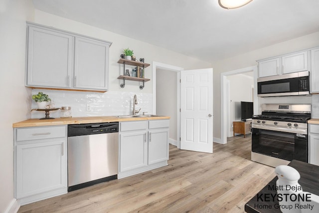109 Leonard St NE, Grand Rapids, MI 49503 - kitchen with stainless steel appliances, a sink, butcher block countertops, open shelves, and decorative backsplash