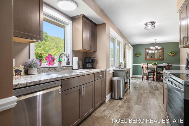 16507 Sleeper St, Grand Haven, MI 49417 - kitchen with appliances with stainless steel finishes, a sink, light wood-style flooring, a chandelier, and hanging light fixtures