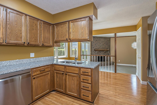 1196 Rathfon Cir, Saline, MI 48176 - kitchen with stainless steel appliances, a sink, a peninsula, light wood-type flooring, and a textured ceiling