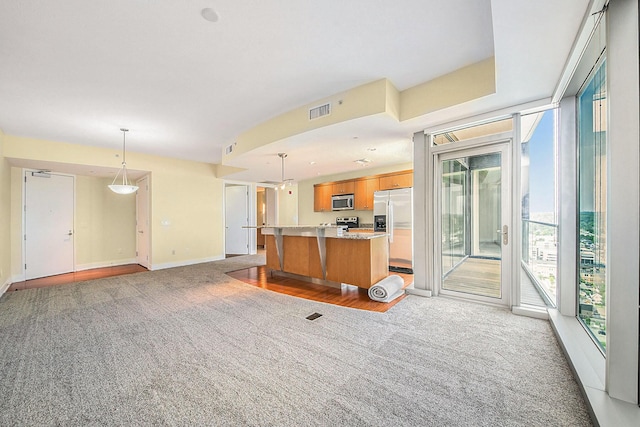 335 Bridge St NW Unit 2005, Grand Rapids, MI 49504 - kitchen featuring stainless steel appliances, light colored carpet, a center island, baseboards, and pendant lighting