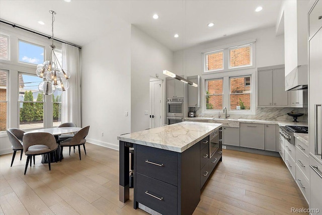 647 Ann St, Birmingham, MI 48009 - kitchen featuring a chandelier, stainless steel appliances, gray cabinets, light wood finished floors, and a high ceiling