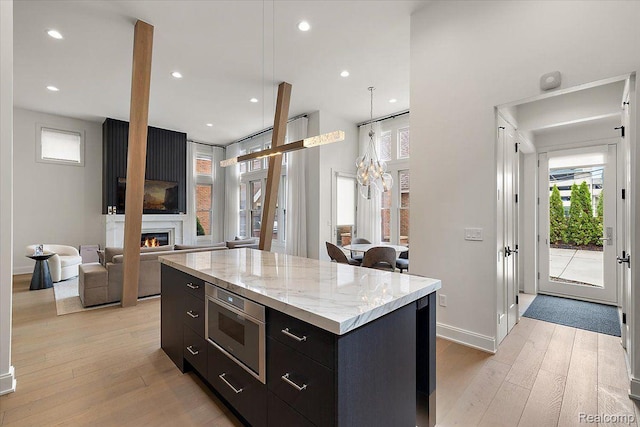 647 Ann St, Birmingham, MI 48009 - kitchen with light wood-style flooring, a center island, a lit fireplace, modern cabinets, and recessed lighting