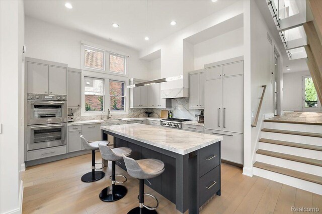 647 Ann St, Birmingham, MI 48009 - kitchen with gray cabinetry, a towering ceiling, double oven, a kitchen bar, and recessed lighting