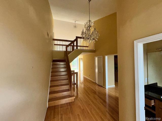 692 Brockmoor Ln, Bloomfield, MI 48304 - stairway featuring wood finished floors, a chandelier, baseboards, and a towering ceiling