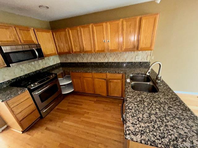 692 Brockmoor Ln, Bloomfield, MI 48304 - kitchen featuring appliances with stainless steel finishes, a sink, backsplash, and light wood-style flooring