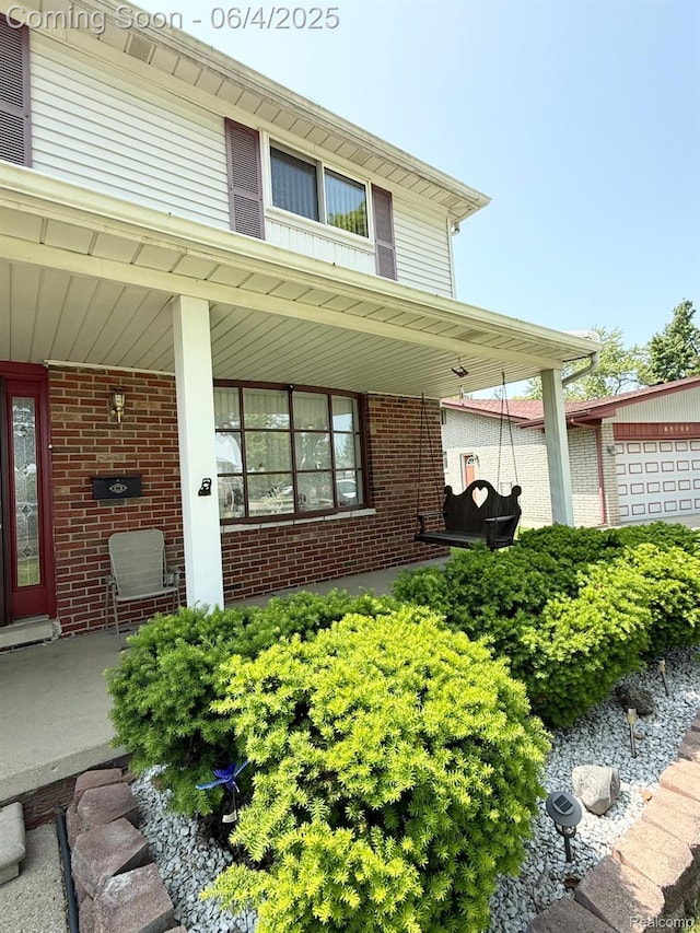 35677 Tina Dr, Warren, MI 48310 - doorway to property with a porch, brick siding, and a garage