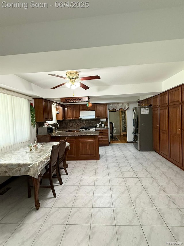 35677 Tina Dr, Warren, MI 48310 - kitchen featuring under cabinet range hood, dark countertops, freestanding refrigerator, backsplash, and light tile patterned floors