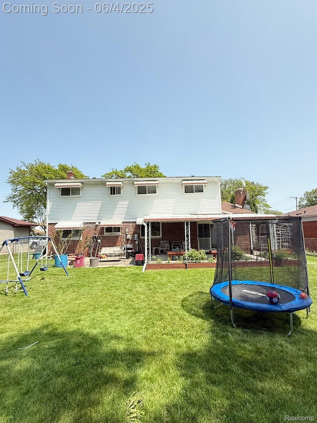 35677 Tina Dr, Warren, MI 48310 - rear view of house with a trampoline, a lawn, brick siding, a patio, and a playground
