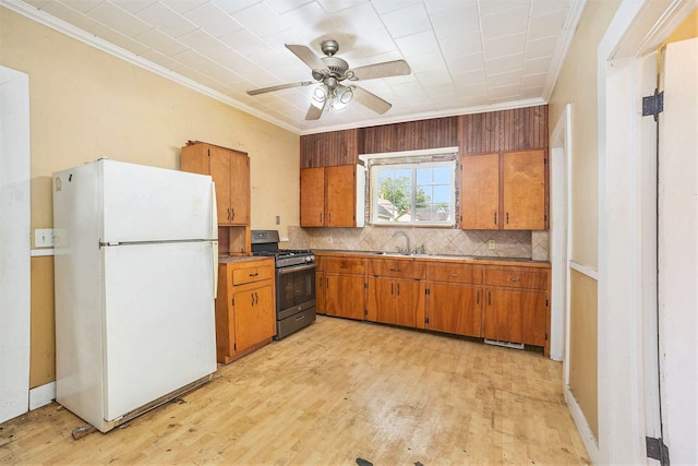 828 Nagold St NW, Grand Rapids, MI 49504 - kitchen featuring freestanding refrigerator, stainless steel gas stove, crown molding, brown cabinets, and backsplash