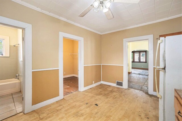 828 Nagold St NW, Grand Rapids, MI 49504 - unfurnished bedroom with freestanding refrigerator, crown molding, light wood-style flooring, ensuite bath, and a walk in closet