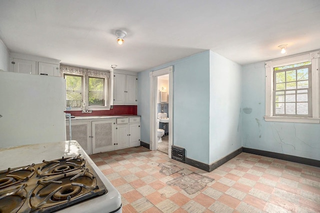 828 Nagold St NW, Grand Rapids, MI 49504 - kitchen with baseboards, white cabinets, plenty of natural light, and light countertops