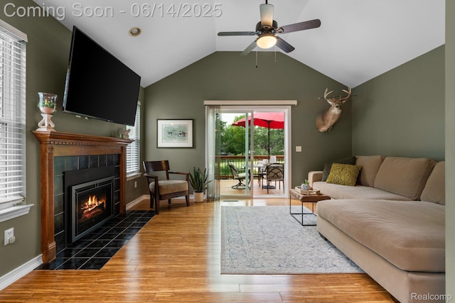 9299 Appleview Ct, Brighton, MI 48116 - living area featuring a tiled fireplace, wood finished floors, ceiling fan, and lofted ceiling
