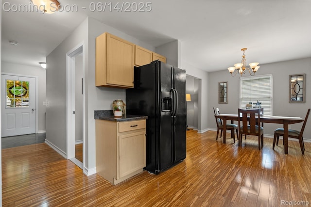 9299 Appleview Ct, Brighton, MI 48116 - kitchen featuring black fridge, light brown cabinetry, wood-type flooring, a chandelier, and plenty of natural light