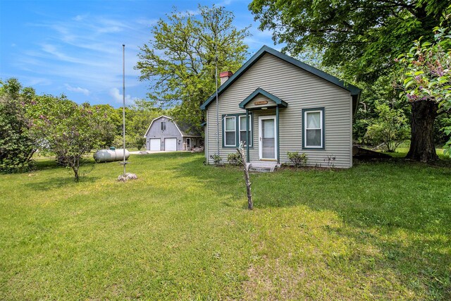 1754 Maggie St, Fountain, MI 49410 - view of front of property featuring a garage, an outbuilding, a chimney, and a front lawn