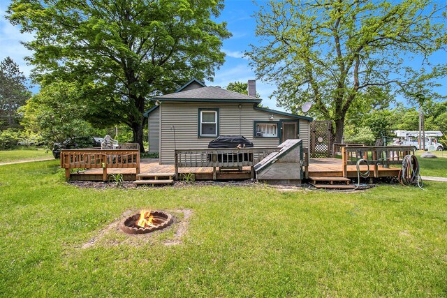1754 Maggie St, Fountain, MI 49410 - back of house with an outdoor fire pit, a chimney, a deck, and a yard