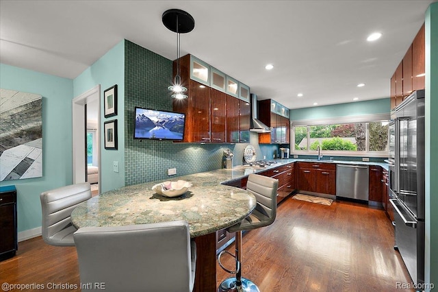 6727 Lahser Rd, Bloomfield Hills, MI 48301 - kitchen featuring stainless steel appliances, wall chimney exhaust hood, dark wood-type flooring, a peninsula, and decorative backsplash