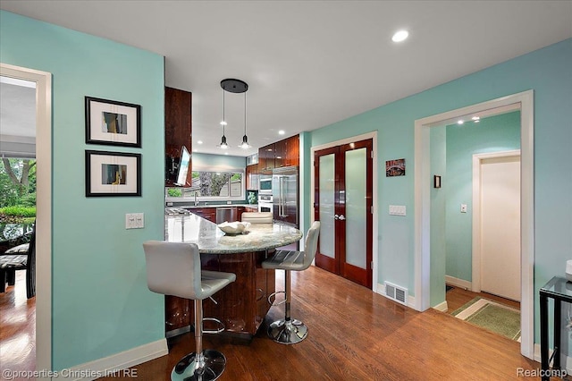 6727 Lahser Rd, Bloomfield Hills, MI 48301 - kitchen featuring baseboards, a breakfast bar, pendant lighting, a peninsula, and light stone counters