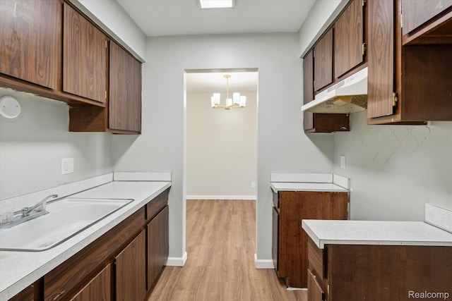 21121 Hayes Ave, Eastpointe, MI 48021 - kitchen with under cabinet range hood, light wood-type flooring, a sink, and light countertops