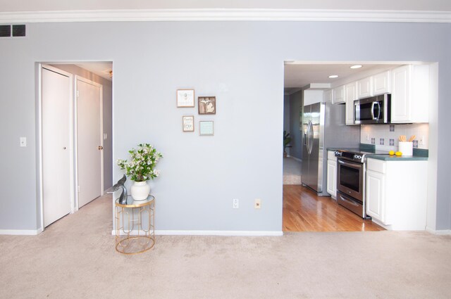 19578 Crystal Lake Dr, Northville, MI 48167 - kitchen featuring appliances with stainless steel finishes, light carpet, ornamental molding, baseboards, and white cabinets
