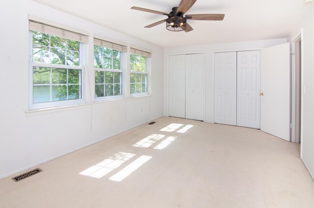 19578 Crystal Lake Dr, Northville, MI 48167 - unfurnished bedroom featuring multiple closets, light carpet, and a ceiling fan