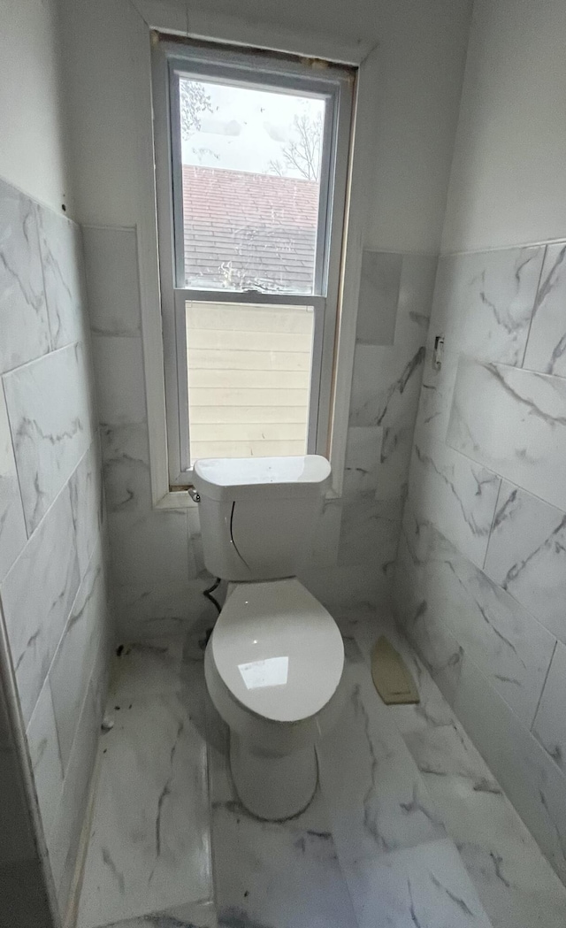 4344 10th St, Ecorse, MI 48229 - bathroom featuring tile walls, toilet, marble look tiles, and a wainscoted wall