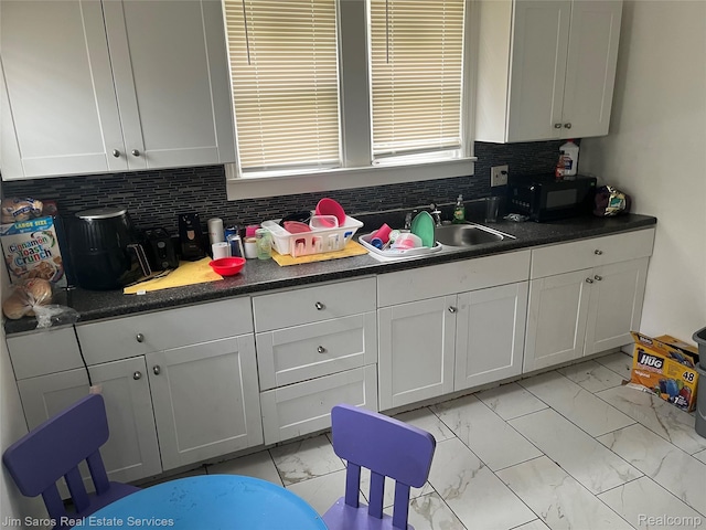 5050 Somerset Ave, Detroit, MI 48224 - kitchen with light marble finish flooring, black microwave, backsplash, white cabinets, and dark countertops