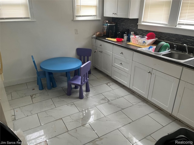 5050 Somerset Ave, Detroit, MI 48224 - kitchen featuring light marble finish floors, a sink, plenty of natural light, and tasteful backsplash