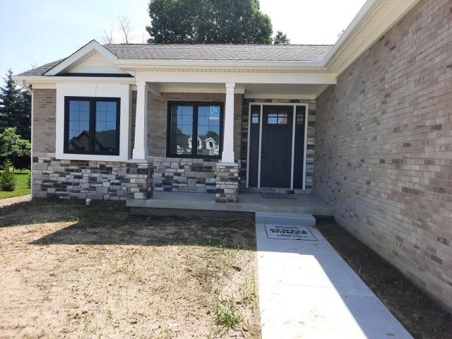 16445 Sleepy Hollow Dr, Fenton, MI 48430 - view of exterior entry with a porch, stone siding, and roof with shingles