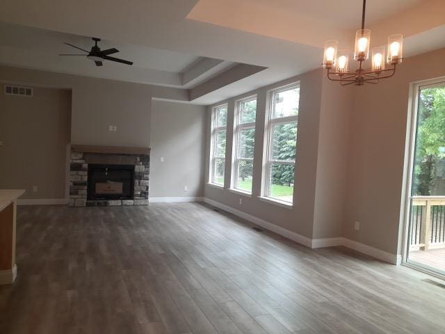 16445 Sleepy Hollow Dr, Fenton, MI 48430 - unfurnished living room featuring wood finished floors, a stone fireplace, a chandelier, ceiling fan, and a tray ceiling
