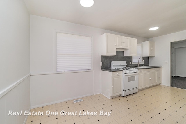 4675 E Parish Rd, Midland, MI 48642 - kitchen with white gas range, light flooring, a sink, dark countertops, and tasteful backsplash