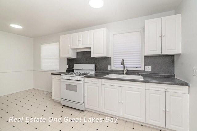 4675 E Parish Rd, Midland, MI 48642 - kitchen with white gas stove, a sink, dark countertops, and light flooring