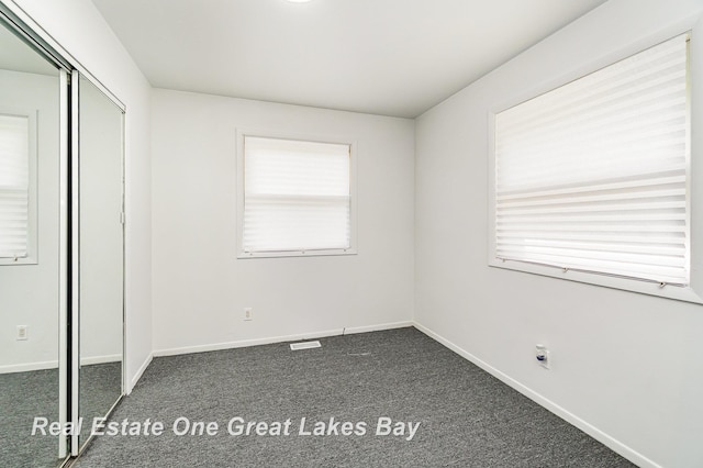 4675 E Parish Rd, Midland, MI 48642 - unfurnished bedroom with dark carpet, baseboards, and a closet