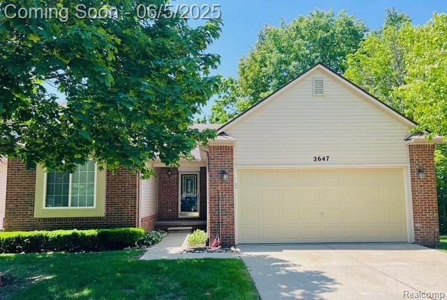 2647 S Moonglow Ct, Hartland, MI 48353 - view of front of home featuring brick siding, a garage, driveway, and a front lawn