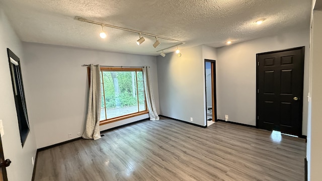 30 Zuidema Ct, Kalamazoo, MI 49001 - unfurnished room featuring track lighting, a textured ceiling, wood finished floors, and baseboards