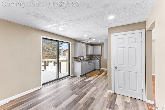 3428 Lennon Rd, Flint, MI 48507 - kitchen featuring gray cabinets, light wood-type flooring, baseboards, tasteful backsplash, and a textured ceiling