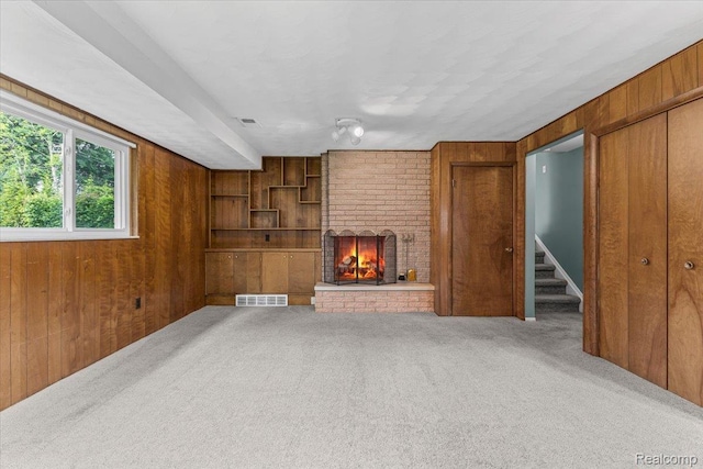 2985 Lacota Rd, Farmington, MI 48328 - unfurnished living room with wood walls, carpet flooring, a fireplace, and stairway