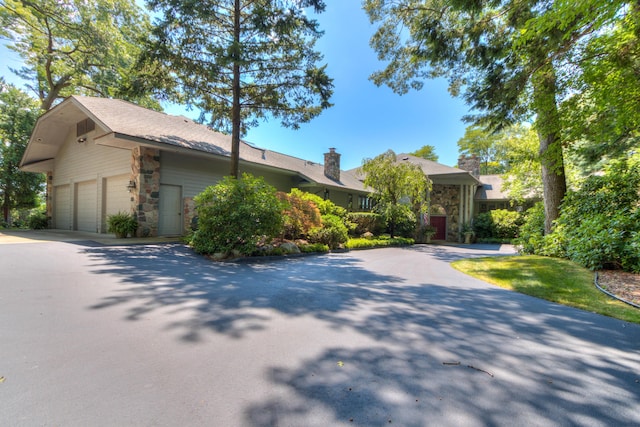 4298 Braeburn Ct, Norton Shores, MI 49441 - view of front facade featuring stone siding, a garage, driveway, and a chimney
