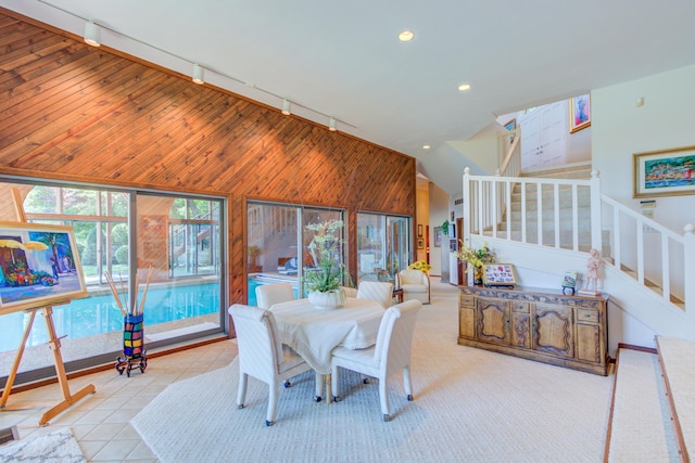 4298 Braeburn Ct, Norton Shores, MI 49441 - dining space featuring rail lighting, stairway, vaulted ceiling, wood walls, and recessed lighting