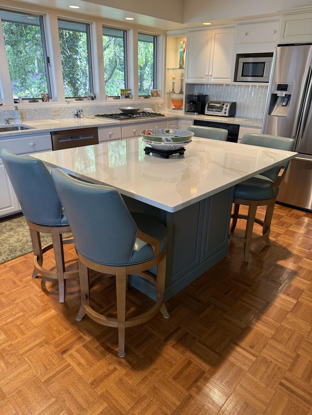 4298 Braeburn Ct, Norton Shores, MI 49441 - kitchen with appliances with stainless steel finishes, white cabinetry, a sink, a kitchen breakfast bar, and recessed lighting