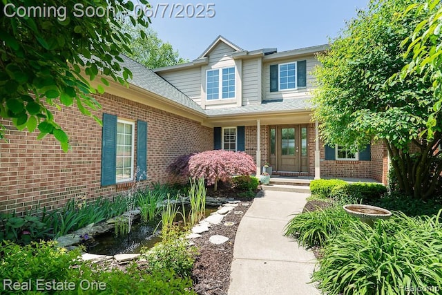 468 Orchard Ridge Dr, Lake Orion, MI 48362 - property entrance featuring a garden pond, brick siding, roof with shingles, and a porch